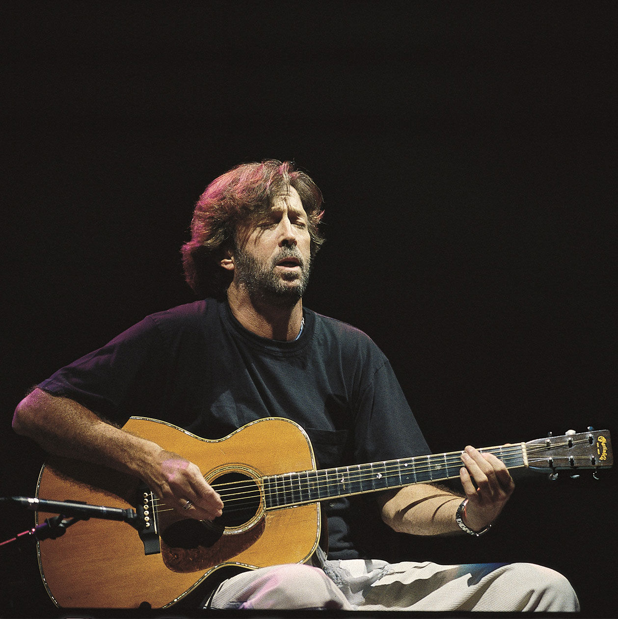 Older photo of Eric Clapton playing an acoustic guitar