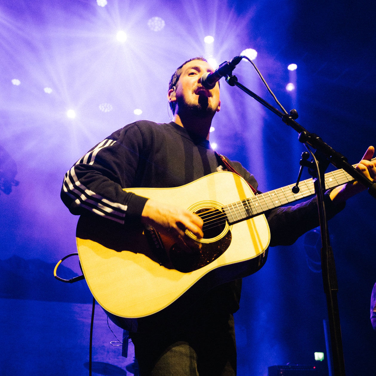 Michael Marcagi playing guitar on a stage with purple lights