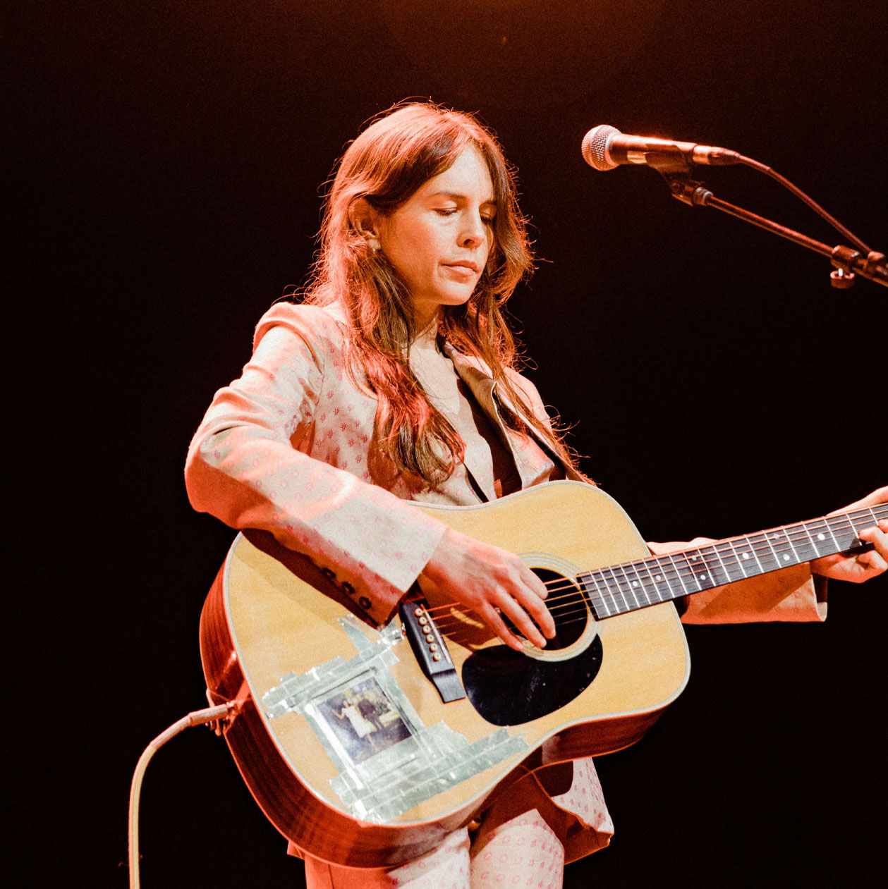 Photo of Madi Diaz on stage playing an acoustic guitar