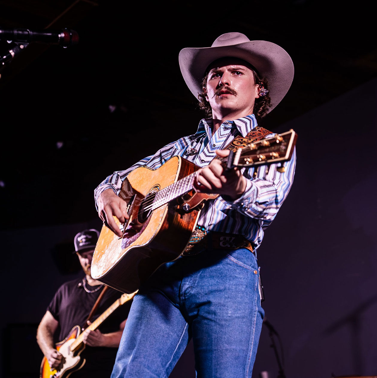 Photo of Braxton Keith in a cowboy hat playing guitar on stage
