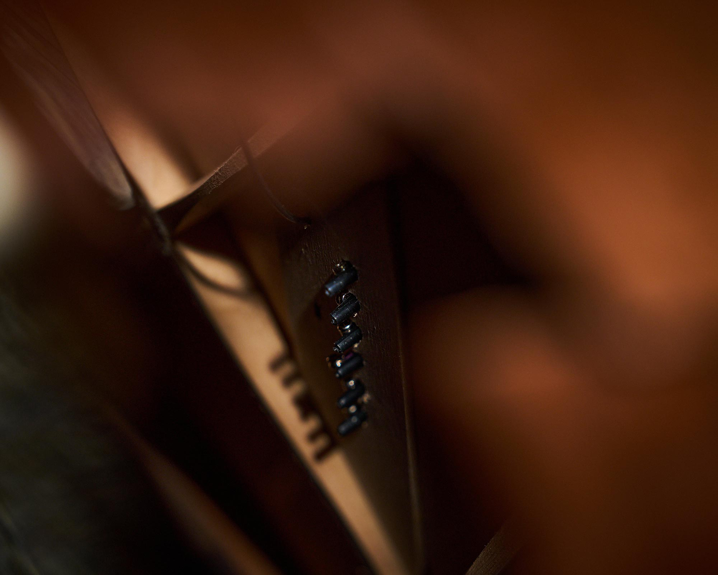 A photo taken inside the acoustic guitar looking up at the bridge pins