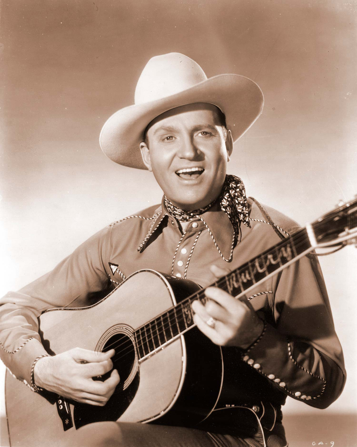A sepia-toned photo of Gene Autry holding his Martin guitar