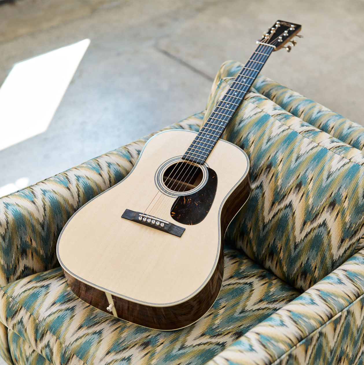Acoustic guitar laying on a chair with colorful upholstery