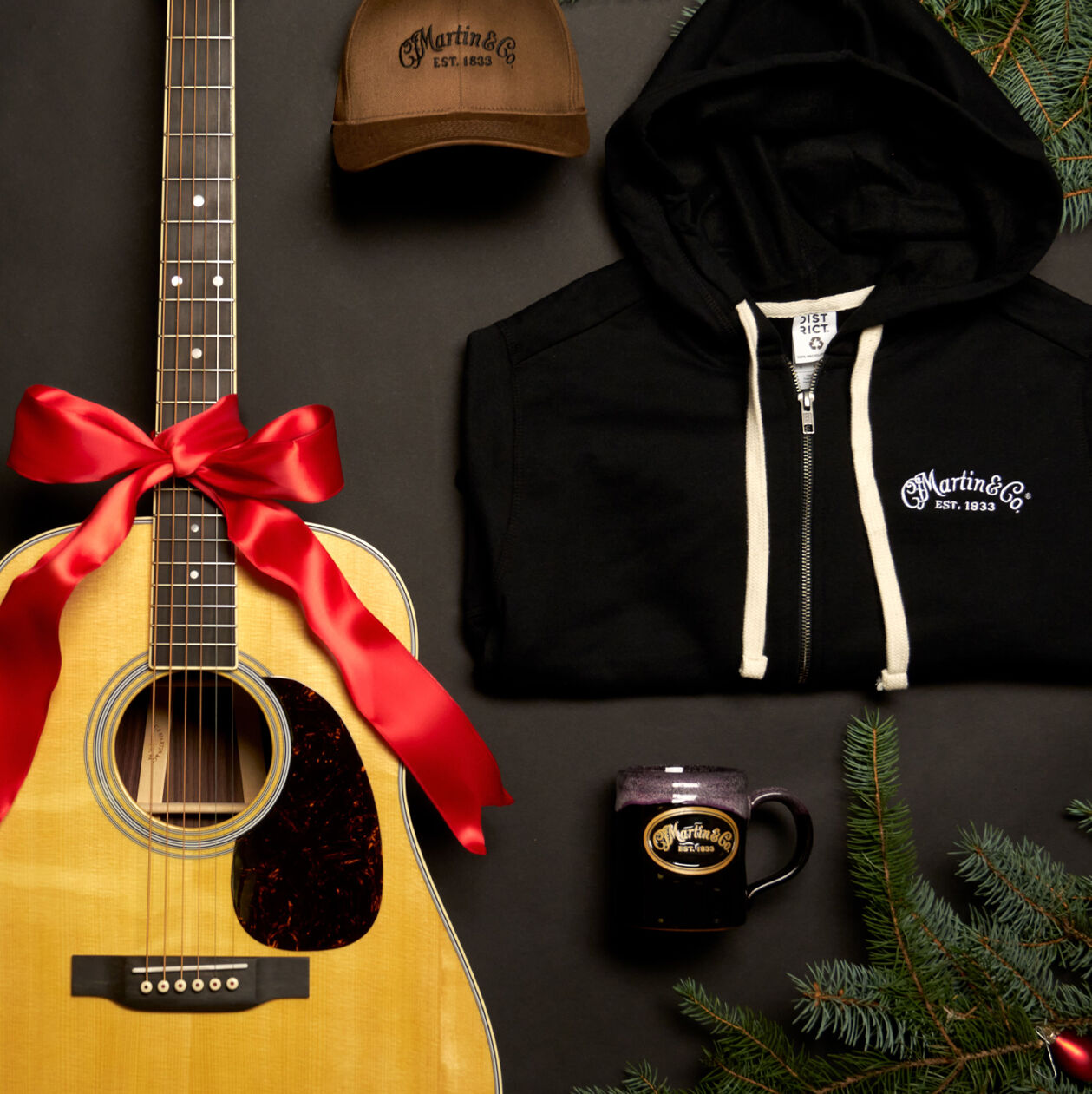 Laydown shot of a guitar, sweatshirt, mug, and hat