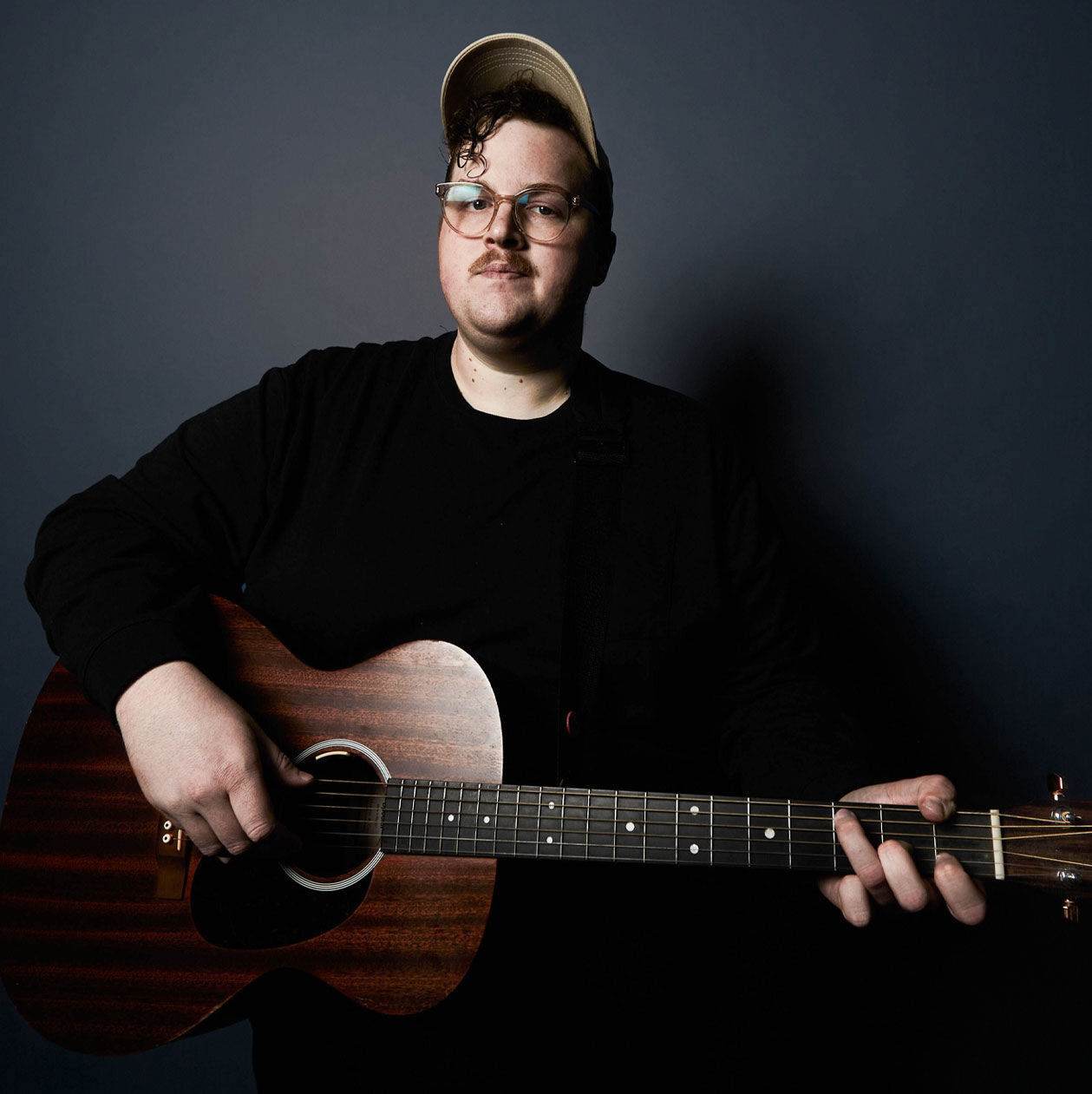 Michigander wearing black and posing with a guitar