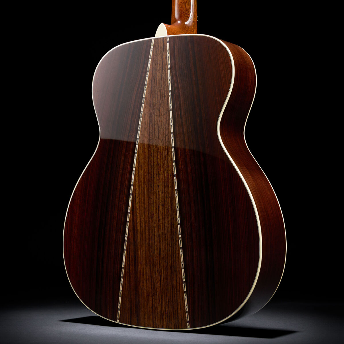 Detail shot of the back of an acoustic guitar, showing two different woods forming an upside down V from the neck