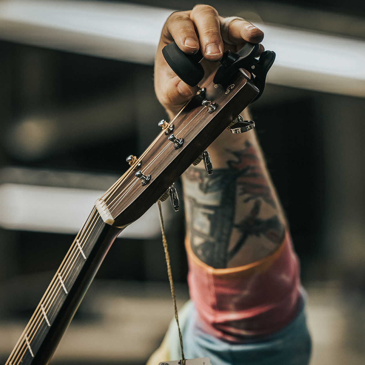 Person adjusting a clip-on tuner on the head of an acoustic guitar
