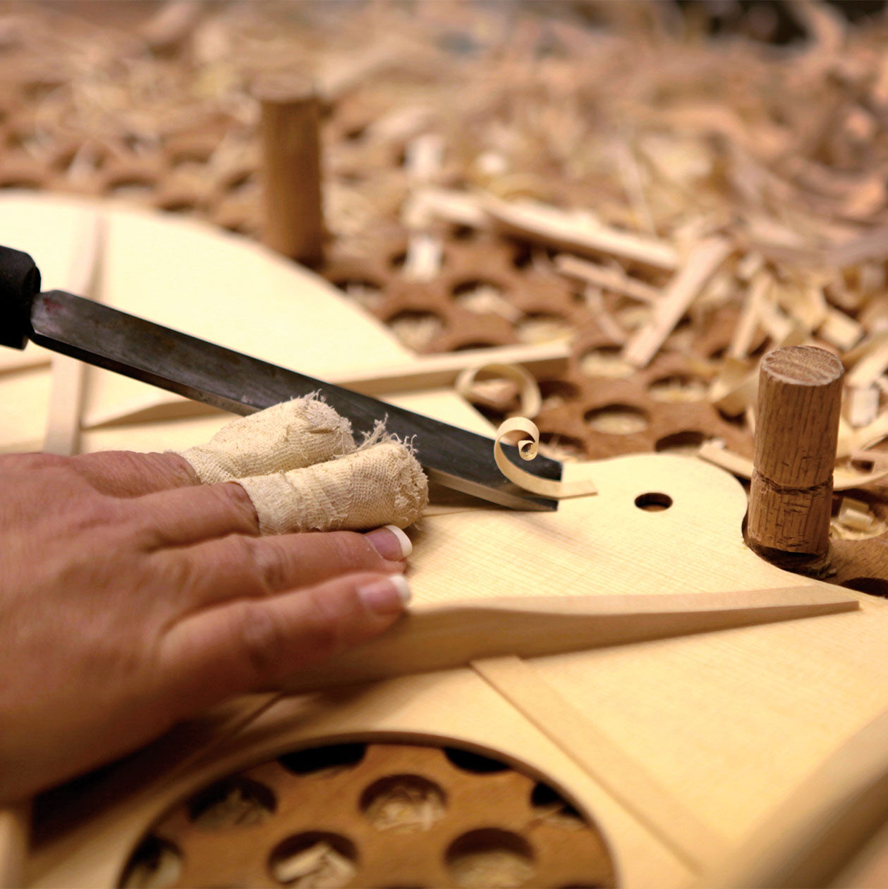 A luthier shaving wood off of guitar bracing