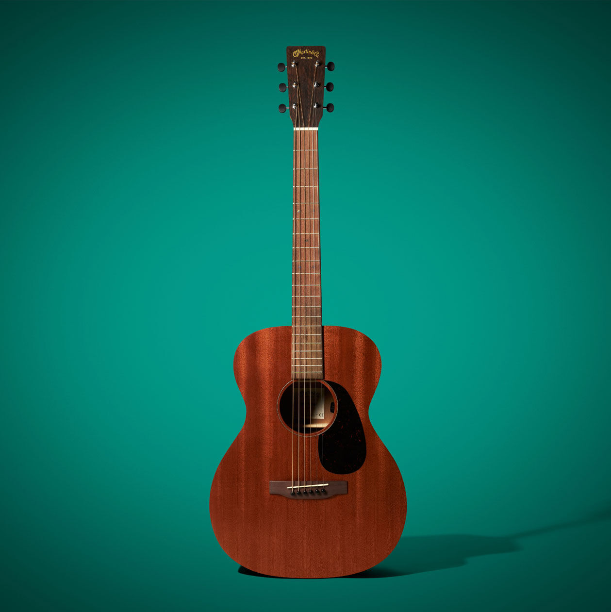 The 000 Jr E acoustic guitar on a Green background