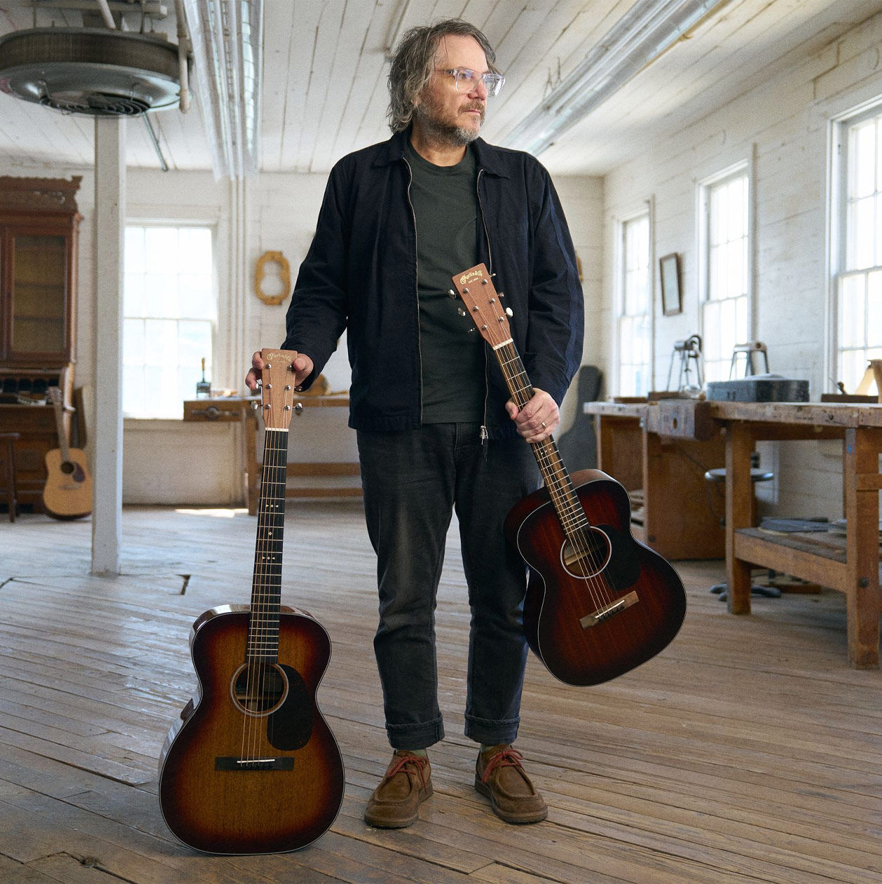 Jeff standing with his guitars in a white room