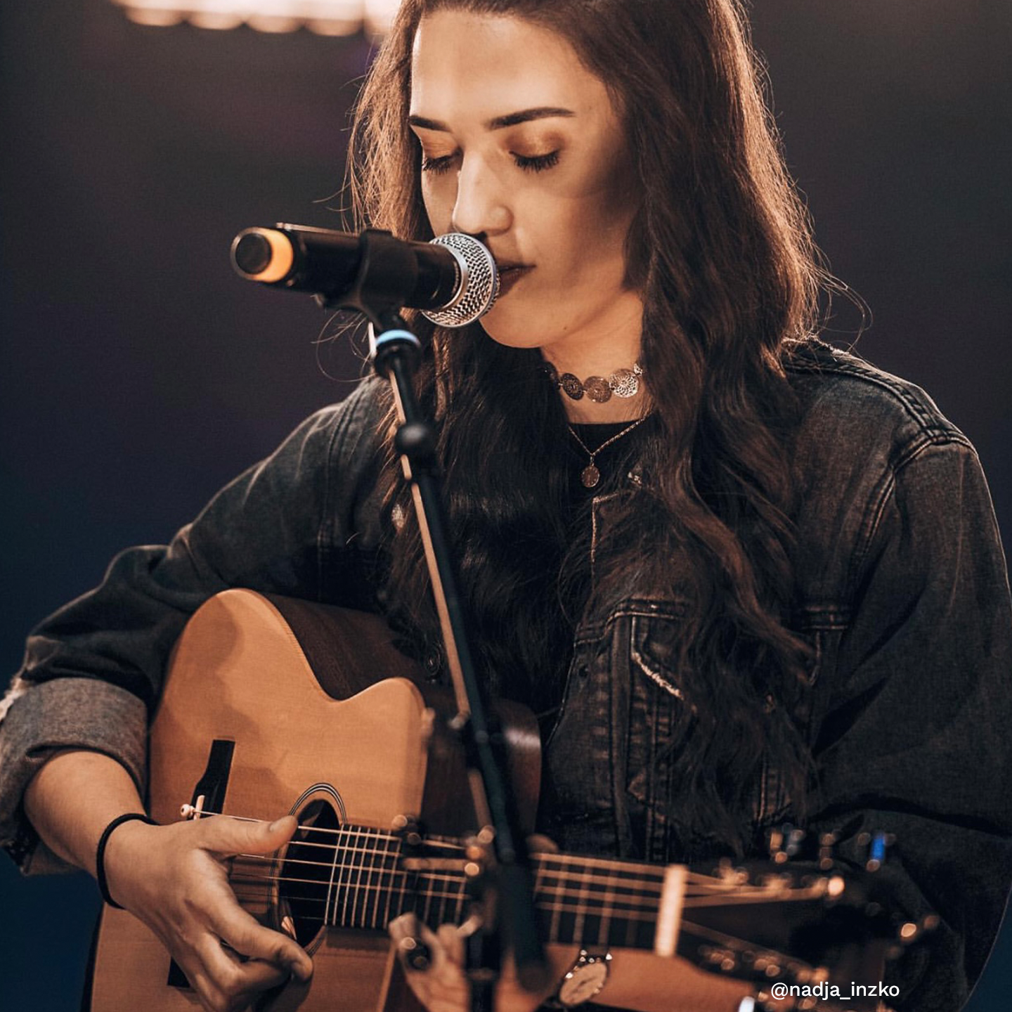 Woman playing guitar at a mic