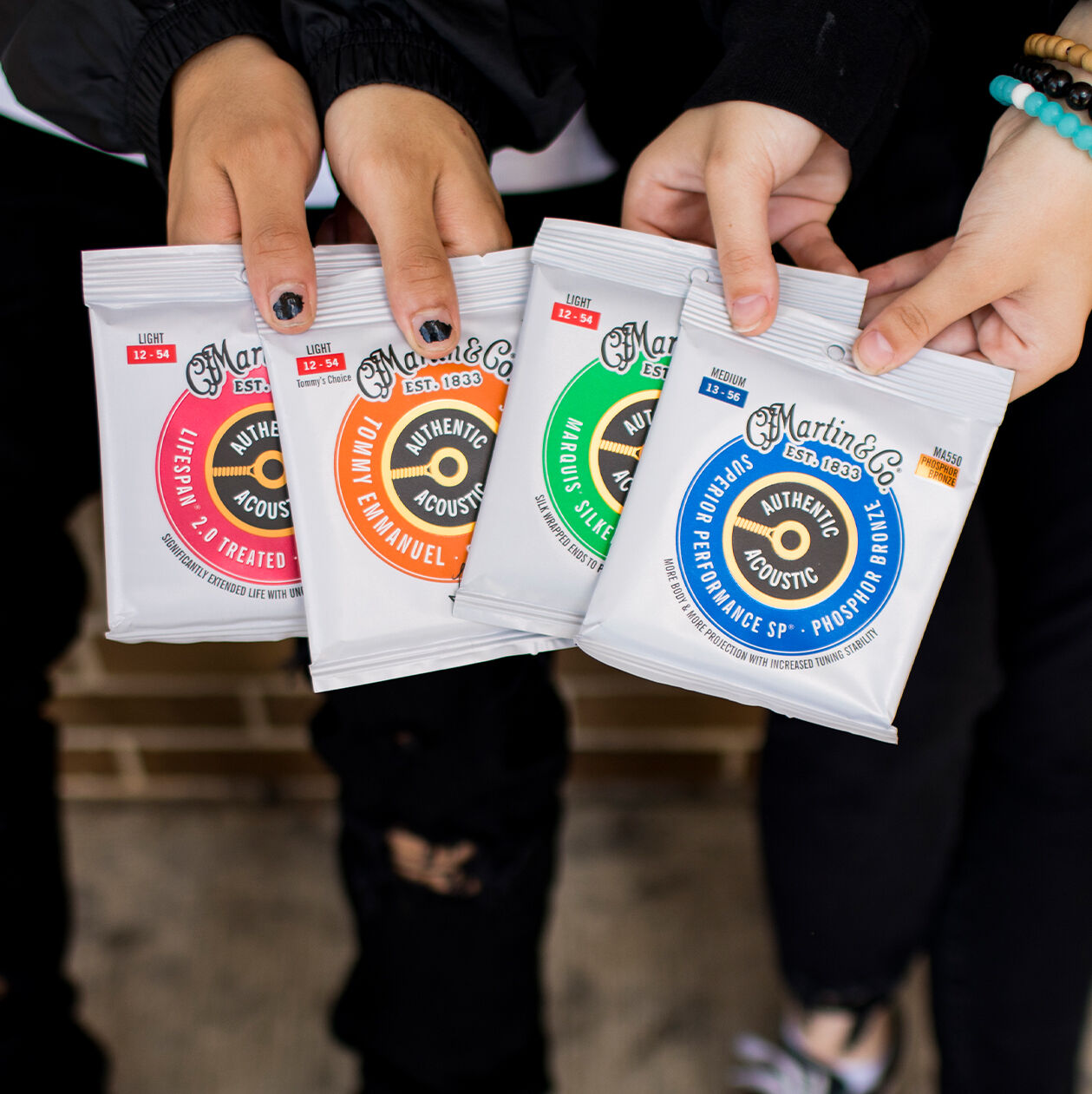 Hands each holding a pack of guitar strings