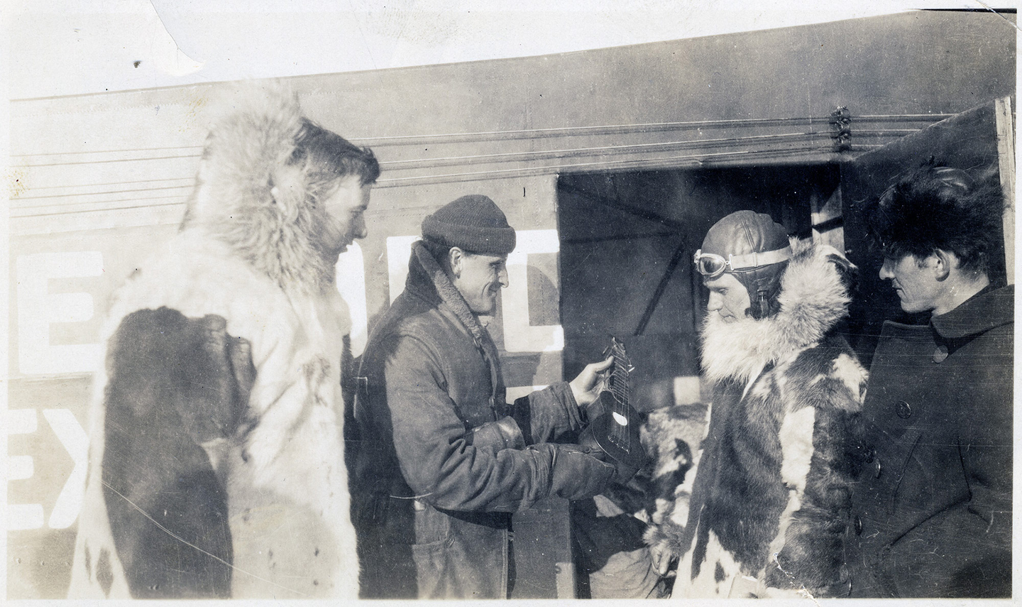 Historical photo of multiple men looking at a ukulele