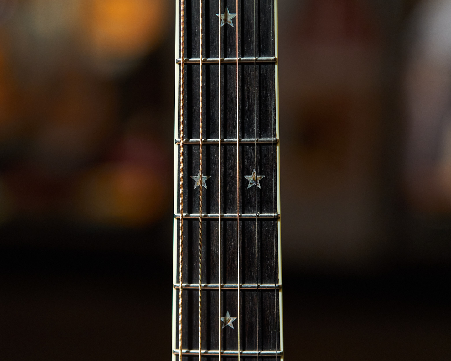 Photo of star shaped inlays on an acoustic guitar neck