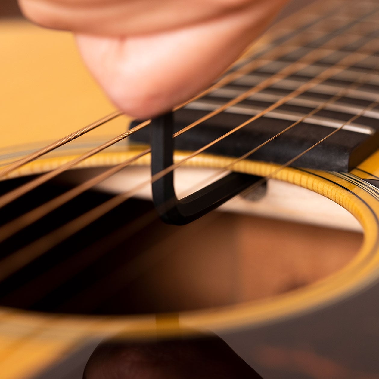 Person holding an allen wrench adjusting the truss rod on an acoustic guitar