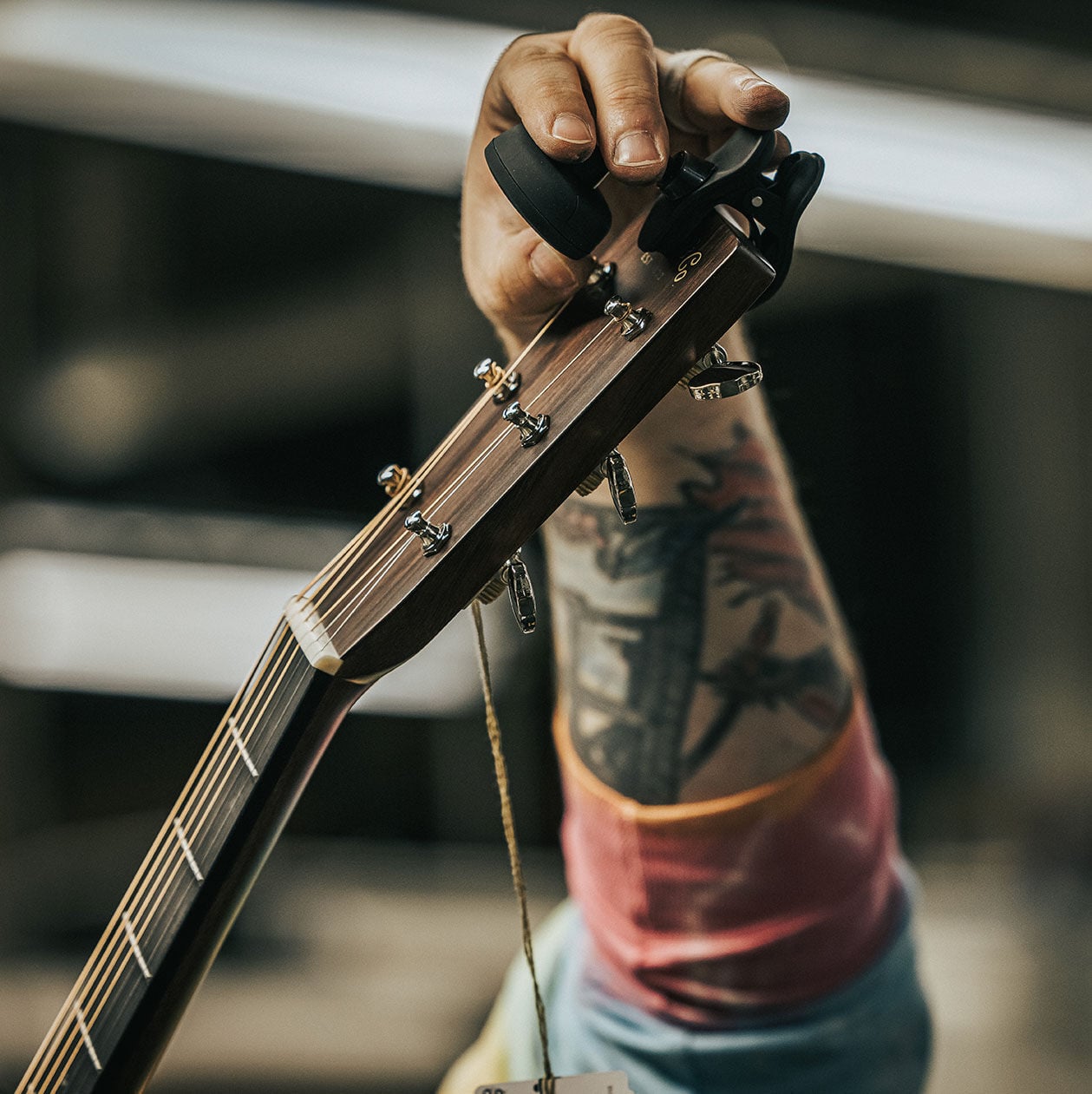 Person adjusting a clip-on tuner on the head of an acoustic guitar
