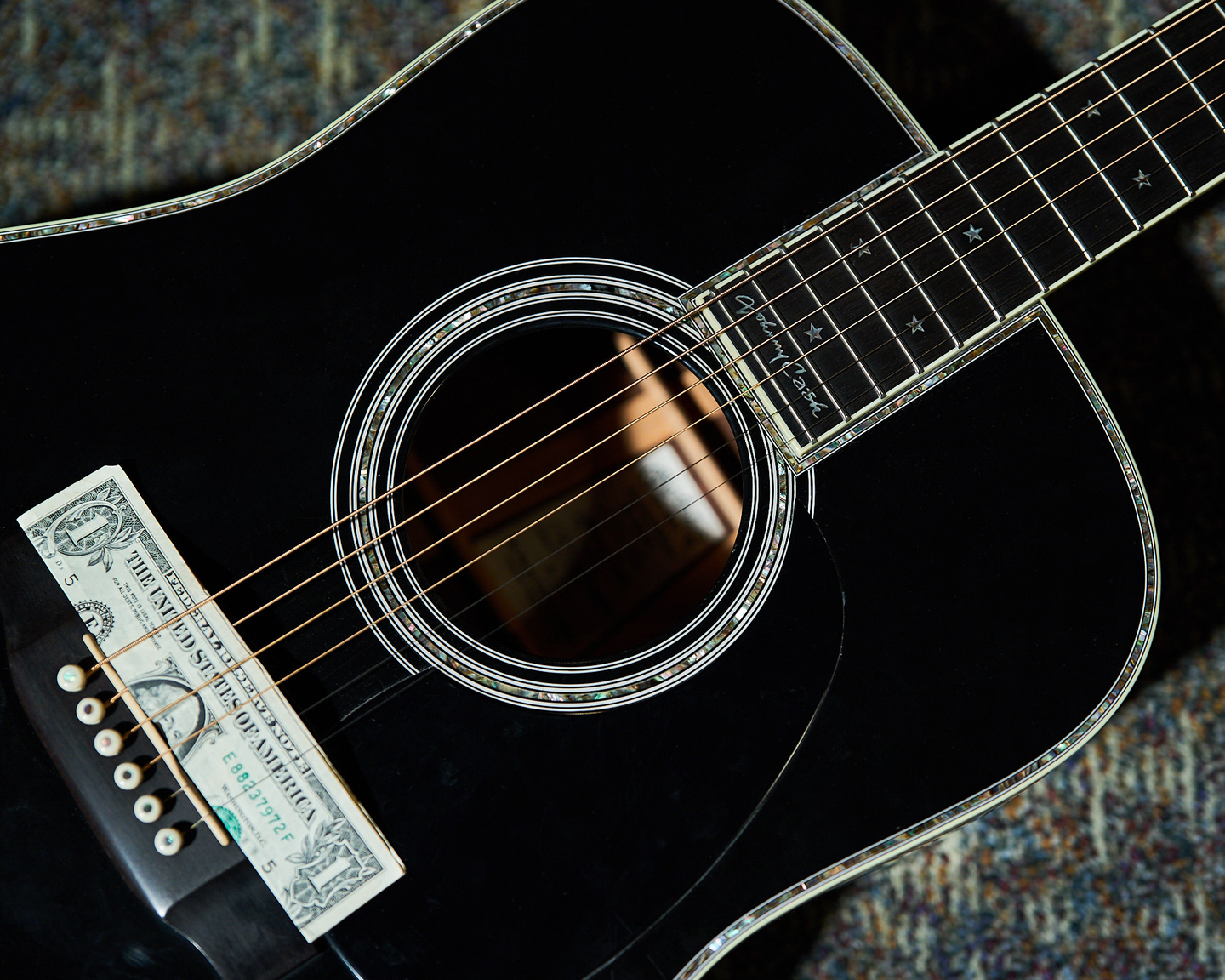 Photo of a folded $1 bill on a black acoustic guitar